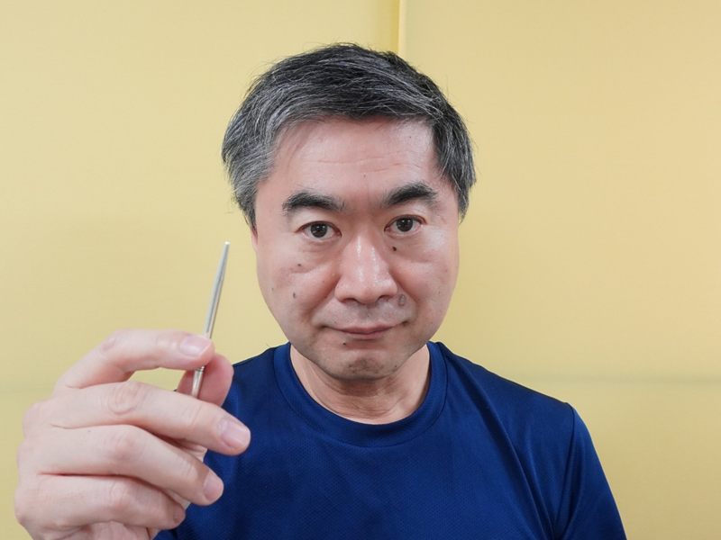 院長 大浦慶文。刺さないはり（てい鍼）を手にしている